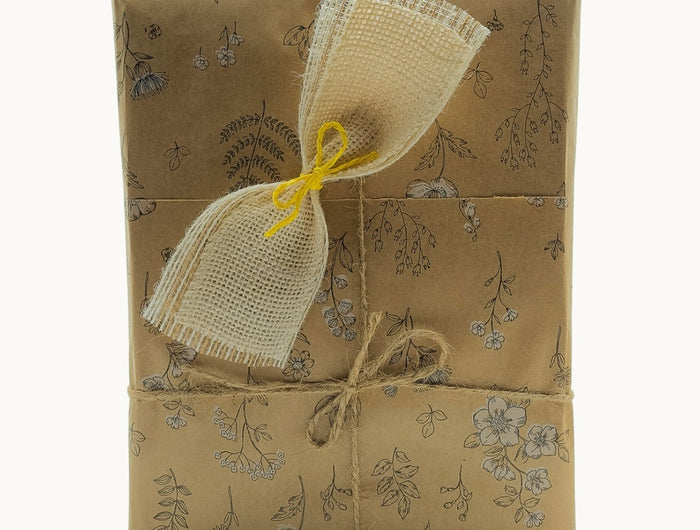 Caja de regalo de productos artesanales gallegos, envuelta en papel Kraft y con un lazo rústico.