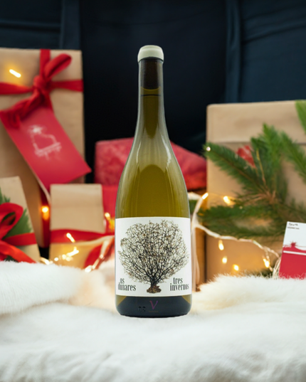 Albariño Tres Invernos sobre un mantel de pelos blanco con unas luces de navidad y regalos y tarjetas.