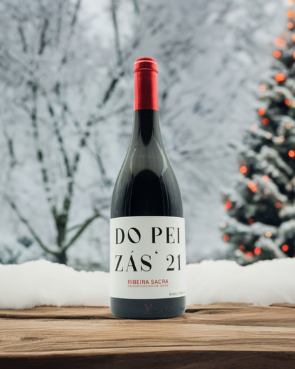 Vino de la Ribeira Sacra Do Peizas 2021 sobre una mesa de madera y un árbol de navidad en un ambiente nevado.