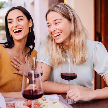Unas amigas charlando en la terraza de un restaurante con unas copas de vino tinto Gallego