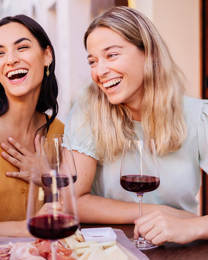 Unas amigas charlando en la terraza de un restaurante con unas copas de vino tinto Gallego