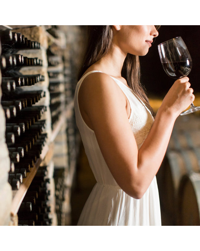 Una chica con un vestido blanco catando un vino tinto en el cellar de una bodega en Galicia
