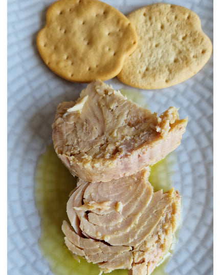 Una receta con bonito del Norte y galletas mariñeiras, sobre un plato con aceite de oliva