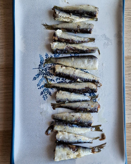 Una receta con sardinillas sobre un plato semi azul