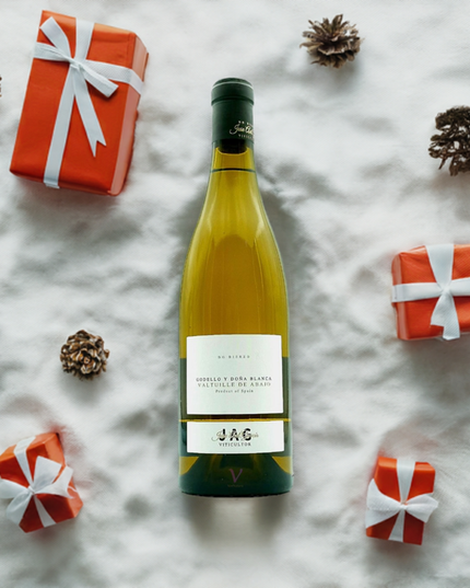 Vino Orgánico Godello y Doña blanca sobre la nieve con regalos Navideños al lado.