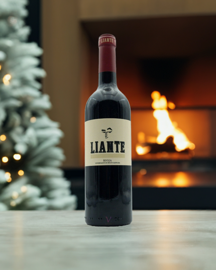 Vino Tinto sobre una mesa clara con un árbol de navidad y una chimenea moderna encendida.