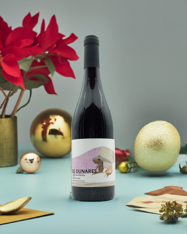 Vino tinto Os Dunares Caiño tinto sobre una mesa de navidad con copas de vino,  bolas de navidad y planta roja de navidad