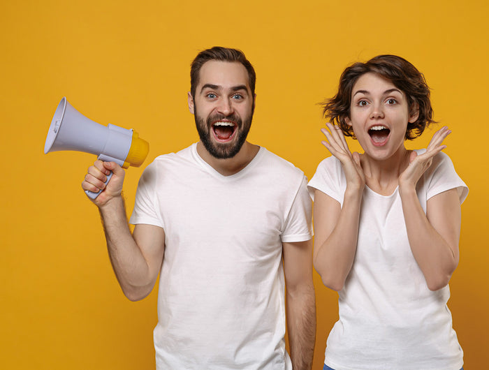 Un a pareja con camisetas blancas y un altavoz, están anunciando las rebajas de los vinos naturales y ecológicos de VinNatura.