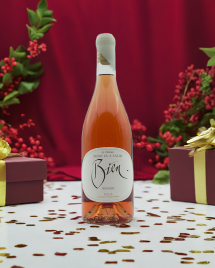 Vino rosado Todo Va a Salir Bien 2023 sobre una mesa blanca y regalos de navidad.