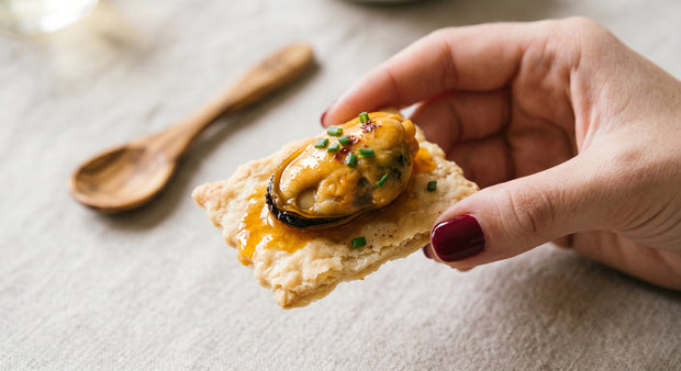 Tostada de un mejillón en escabeche en una mariñeira sujetado por la mano de una chica